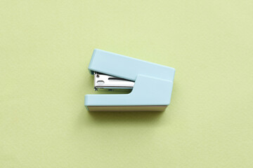 Blue stapler on green background