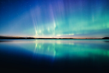 Northern lights dancing over calm lake in north of Sweden