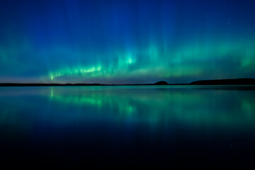 Northern lights dancing over calm lake in north of Sweden