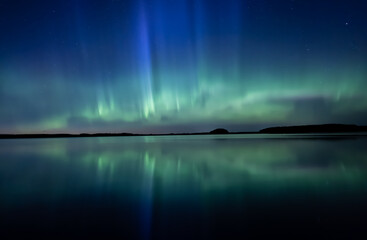 Northern lights dancing over calm lake in north of Sweden