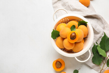 Colander full of ripe apricots on light background