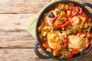 Ivory Coast food Chicken slowly stewed with vegetables and herbs close-up in a frying pan on the table. Horizontal top view from above