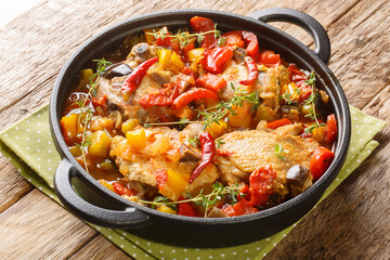 Ivory Coast food Chicken slowly stewed with vegetables and herbs close-up in a frying pan on the...