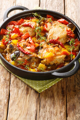 Chicken slowly stewed with vegetables and herbs close-up in a frying pan on the table. Vertical