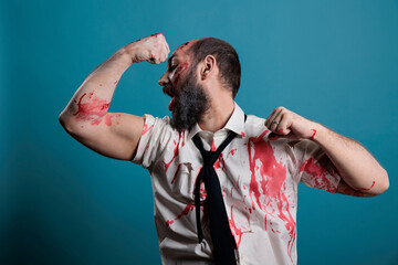 Spooky halloween monster flexing arm muscles on camera, showing biceps and triceps while acting...