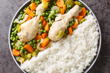 Chilean food Pollo arvejado chicken stew with carrots and green peas served with rice close-up in a plate on the table. Horizontal top view from above
