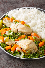 Peas and carrots Chicken Stew Pollo Arvejado with rice garnish closeup in the plate on the table. Vertical