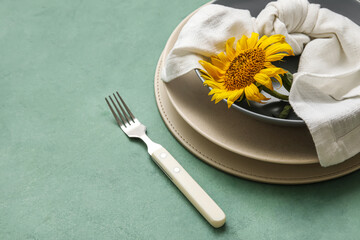 Dinnerware and sunflower in plate on green table