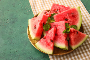 Plate with pieces of ripe watermelon with mint on color background