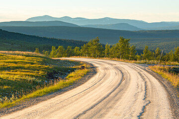 Fototapeta na wymiar Curve on a dirt road with a scenic view of a forest landscape with the mountains on the horizon