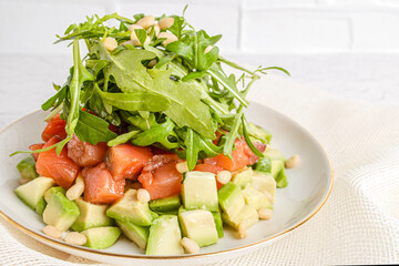 salmon, avocado and arugula salad decorated with pine nuts on a plate
