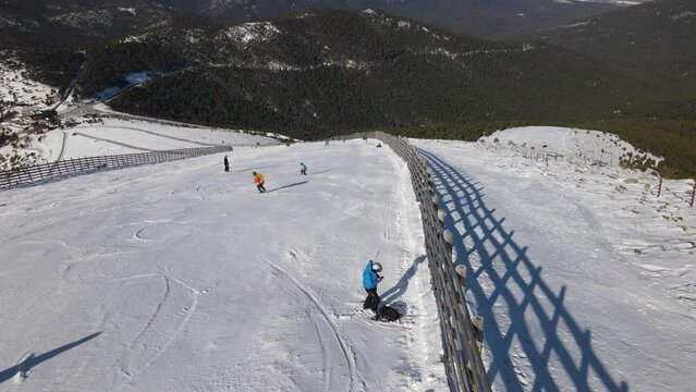 Person stopped in a ski slope. Other people are skiing on a snow covered mountain on a sunny winter day.