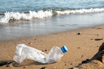 Spilled garbage on the beach of the big city. Empty used dirty plastic bottles. Dirty sea sandy shore the Black Sea. Environmental pollution. Ecological problem. Bokeh moving waves in the background