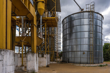 Obraz premium row of agro silos granary elevator with seeds cleaning line on agro-processing manufacturing plant for processing drying cleaning and storage of agricultural products