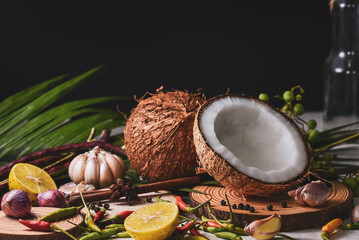 The halved coconut is placed near various spices.