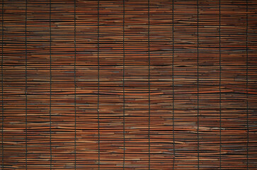 Close up of reddish bamboo screen. Blind made of split bamboo or reeds fastened together with thread.