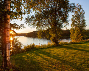 Sunset scenery on an autumn evening in Finland. Lake shore wallpaper concept image. Some flare effect added to images.