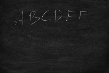 Abstract hand writing English alphabet with chalk on blackboard. letters A B C to Z on a black chalkboard.