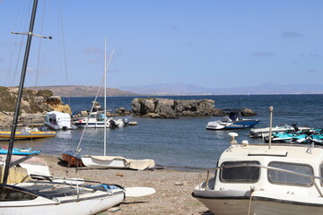 Boats in the port on a sunny summer day, you can see the yellow rocks, palms and houses. Tabarca Island in Spain.