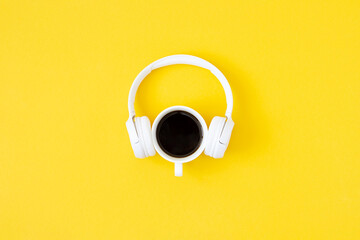 A cup of black coffee and white headphones on yellow background. Minimal style, Flat lay, Top view....