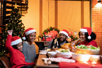 African american colored family decoration gift box in background on festive christmas tree and cheerful serving roasted turkey dinner and red wine with set of food fruit and sweet desert on table