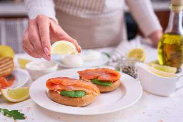 woman squeezing lemon juice on a Cream cheese and Smoked salmon toast