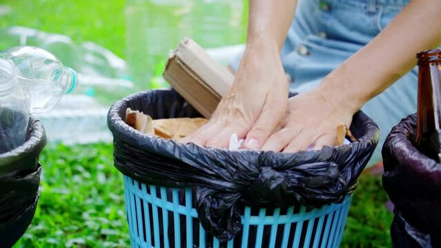 Young woman sorting papper trash in the yard of the house