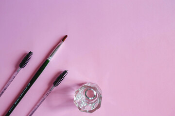 Materials for depilation of eyebrows on a pink background. Wooden stick for wax, brushes, brush for...