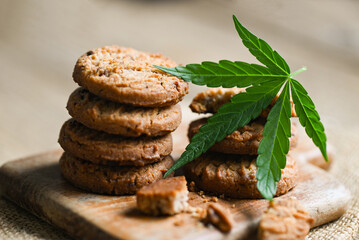 Cannabis food cookies with cannabis leaf marijuana herb on wooden background, delicious sweet dessert cookie with hemp leaf plant THC CBD herbs food snack and medical