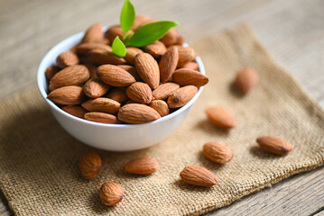 Almonds nuts on white bowl and green leaf on sack backgroundม, Delicious sweet almonds on the...