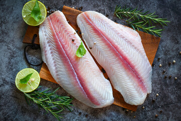 fresh raw pangasius fish fillet with herb and spices black pepper lemon lime, fish fillet on wooden board with ingredients for cooking, meat dolly fish tilapia striped catfish