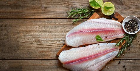 fresh raw pangasius fish fillet with herb and spices black pepper lemon lime, fish fillet on wooden...