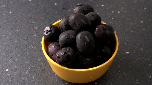 Jambul or Jamun (Syzygium cumini) in yellow bowl isolated on textured background.