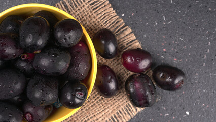 Jambul or Jamun (Syzygium cumini) in yellow bowl isolated on textured background.