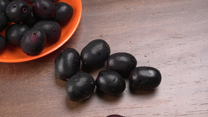 Jambul or Jamun (Syzygium cumini) in yellow bowl isolated on textured background.