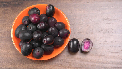 Jambul or Jamun (Syzygium cumini) in yellow bowl isolated on textured background.