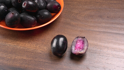 Jambul or Jamun (Syzygium cumini) in yellow bowl isolated on textured background.
