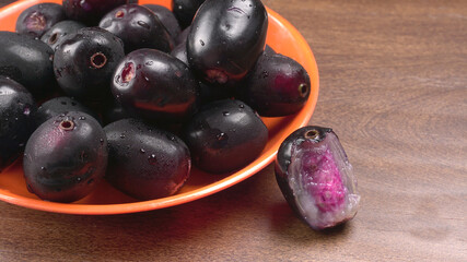 Jambul or Jamun (Syzygium cumini) in yellow bowl isolated on textured background.