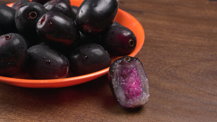 Jambul or Jamun (Syzygium cumini) in yellow bowl isolated on textured background.