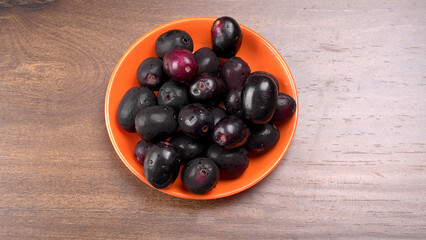 Jambul or Jamun (Syzygium cumini) in yellow bowl isolated on textured background.
