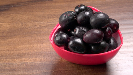 Jambul or Jamun (Syzygium cumini) in yellow bowl isolated on textured background.