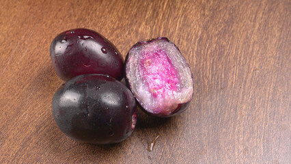 Jambul or Jamun (Syzygium cumini) in yellow bowl isolated on textured background.