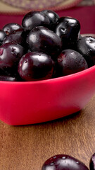 Jambul or Jamun (Syzygium cumini) in yellow bowl isolated on textured background.