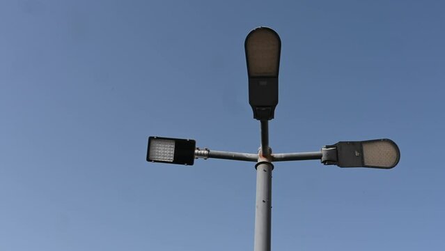 4K: Led streetlight on the high metal pole under the clear blue sky, modern electric led street light pole, low angle shot