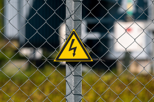 Yellow triangle with lightning on metal fence