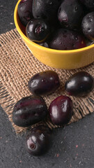 Jambul or Jamun (Syzygium cumini) in yellow bowl isolated on textured background.