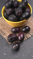 Jambul or Jamun (Syzygium cumini) in yellow bowl isolated on textured background.