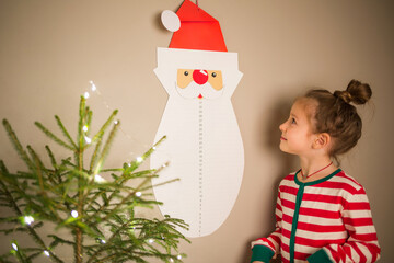 advent calendar in form of Santa Claus beard on wall and child. christmas craft for kids. cut off...
