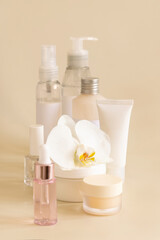 Fototapeta na wymiar Natural cosmetic jars and skin care accesories with white orchid flower on beige close up