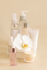 Natural cosmetic jars and skin care accesories with white orchid flower on beige close up